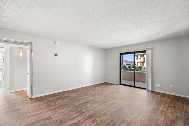 an empty living room with a sliding glass door to a balcony - Sundancer Apartments