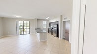 Located at City Hall Promenade in Miramar, FL, this single-floor residence offers three bedrooms, two bathrooms, and a thoughtfully arranged layout. The open-concept living and dining area features large-format light tile flooring and a ceiling fan, with expansive sliding glass doors providing direct balcony access and abundant natural light with views of surrounding greenery.

The kitchen is a functional centerpiece, featuring dark cabinetry, granite countertops, a peninsula with a sink, tile backsplash, and stainless steel appliances including a refrigerator, range, and microwave. A skylight adds additional brightness to the space.

The three bedrooms are carpeted and each includes a window allowing natural light. The primary bedroom offers a comfortable footprint with access to a dedicated closet featuring wire shelving systems. The two bathrooms are finished consistently, each with granite-topped dark vanities, large mirrors, tile flooring, and a tub-shower combination.

Two closets provide practical storage throughout the residence. Neutral gray-toned walls and clean white trim carry a cohesive, understated aesthetic across all rooms.