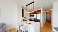 Located at 365 North Halsted Street in Chicago's vibrant Fulton River District, this well-appointed one-bedroom, one-bathroom residence offers a thoughtfully designed open-concept layout. Light wood flooring flows throughout, complementing the clean, contemporary aesthetic.

The combined living, dining, and kitchen area forms the heart of the home. The kitchen is outfitted with rich walnut-toned cabinetry, a striking marble-style waterfall island with bar seating, stainless steel appliances including a gas range and French door refrigerator, and a sleek pendant light fixture overhead. A compact dining nook sits adjacent, ideal for intimate meals.

The living room benefits from expansive floor-to-ceiling windows that flood the space with natural light and frame sweeping Chicago skyline views, creating a bright, airy atmosphere.

The bedroom is generously sized, featuring large picture windows with city views, light wood flooring, a dedicated closet with built-in shelving, and a second access door. The bathroom is finished with elegant marble-style tile throughout the walk-in glass shower, accented by matte black fixtures, offering a refined, spa-like feel.

A dedicated closet provides additional storage, completing this efficient and stylish urban residence.