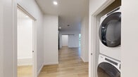 Located at 403 N 1st St in Rogers, Arkansas, this thoughtfully designed 2-bedroom, 2-bathroom residence offers a clean, modern aesthetic across a well-organized single-floor layout. Light wood flooring flows throughout the entire unit, creating a warm and cohesive feel from room to room.

The open-concept kitchen and living area serves as the heart of the home. The kitchen is outfitted with sage green cabinetry, granite countertops, subway tile backsplash, stainless steel appliances, and a deep undermount sink. A standout sliding barn door connects the main living space to the rest of the unit, adding a contemporary architectural detail. Built-in open shelving near the living area offers practical display and storage space. Large floor-to-ceiling windows flood the living room with natural light and provide views of the surrounding neighborhood.

Both bedrooms are bright and well-proportioned, with ceiling fans and sizable windows. The primary bedroom connects to a spacious walk-in closet with built-in shelving and hanging rods, as well as a private en-suite bathroom featuring a dual-sink vanity with granite countertops, sage green cabinetry, and a walk-in shower. The second bathroom includes a full soaking tub with an overhead rain showerhead. A dedicated hallway laundry closet houses a stacked Whirlpool washer and dryer for added convenience.