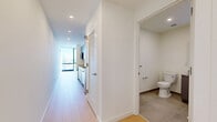 Located at 632 Newark Avenue in Jersey City, NJ, this modern unit offers a thoughtfully designed layout that maximizes every square foot. The living room is bathed in natural light from expansive floor-to-ceiling windows that frame impressive panoramic city skyline views, creating a bright and airy atmosphere throughout. Light-toned hardwood flooring runs seamlessly across the living spaces, complementing the clean, minimalist aesthetic of the interior.

The kitchen is outfitted with sleek gray cabinetry extending to the ceiling for ample storage, a white subway tile backsplash, light quartz countertops, and stainless steel appliances including a built-in over-the-range microwave. The space flows efficiently into the main living area, making it ideal for everyday living.

A well-lit hallway connects the rooms, lined with louvered closet doors offering convenient storage access. Two dedicated closets provide generous built-in storage. The bathroom features tile flooring and a clean, functional design. In-unit laundry adds a practical convenience. Crisp white walls throughout, recessed lighting in the hallway, and a consistent modern finish give the entire unit a polished, move-in ready feel.
