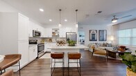 This thoughtfully designed 2-bedroom, 3-bathroom residence offers a cohesive, modern aesthetic across a single floor. Dark hardwood-style flooring flows seamlessly throughout, anchoring the open-concept living area that connects the kitchen, dining, and living spaces. The kitchen is a standout feature, showcasing bright white shaker cabinetry, granite countertops, a subway tile backsplash, stainless steel appliances, and a central island with bar seating illuminated by elegant pendant lighting. The living room is bright and welcoming, with large windows that invite natural light and provide outdoor views. A dedicated dining area comfortably accommodates a dining set alongside the living space. Each bedroom is generously sized, including a spacious primary bedroom, both featuring large windows and continued hardwood-style flooring. The three bathrooms include clean, contemporary finishes, with at least one featuring a glass-enclosed walk-in shower with large-format tile. A dedicated in-unit laundry room with full-size washer and dryer adds everyday convenience. Multiple hallways connect the rooms efficiently, and a closet provides additional storage. The overall ambiance is clean, bright, and modern, with a neutral color palette that enhances the sense of openness throughout.
