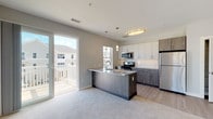 Located along Wareham Road in Plymouth, Massachusetts, this single-floor residence offers a thoughtfully designed layout with contemporary finishes throughout. The open-concept kitchen and living area serves as the heart of the home, featuring a central island with granite countertops, two-tone cabinetry combining crisp white uppers with warm wood-toned lowers, stainless steel appliances including a gas range, microwave, and refrigerator, and light hardwood-style flooring. Pendant lighting and a flush ceiling fixture illuminate the space, while a sliding glass door provides direct access to a private balcony with outdoor views.

The living area transitions seamlessly from the kitchen, offering plush carpeting, neutral walls, and ample natural light. Bedrooms continue the carpeted aesthetic, each equipped with windows that bring in natural light and views of the surrounding neighborhood. One bedroom features a ceiling fan for added comfort.

Two bathrooms serve the residence: one with a full soaking tub and shower combination, and a second designed with accessibility in mind, featuring grab bars, a walk-in shower, and tile flooring. Both bathrooms include granite-topped vanities with modern cabinetry. Additional storage is provided through built-in closets visible throughout the unit, contributing to the home's practical and clean overall design.