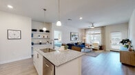 This single-floor residence is thoughtfully designed with a clean, contemporary aesthetic throughout. The open-concept layout seamlessly connects the kitchen, dining, and living areas, creating a cohesive and functional living space. The kitchen is well-equipped with white shaker cabinetry, granite countertops, stainless steel appliances, a subway tile backsplash, and a central island with seating — illuminated by stylish pendant lighting overhead. Built-in open shelving adds both storage and display space to the kitchen area. Light wood-style flooring runs throughout the main living areas, contributing to an airy, modern feel. The living room is generously sized and bathed in natural light from large windows and a sliding glass door that opens to an outdoor area. A ceiling fan and recessed lighting keep the space comfortable and well-lit. The bedroom features plush carpeting, a large window with neighborhood views, and ample room for a full furniture arrangement. Two bathrooms echo the home's design language with granite-topped white vanities, light wood-look flooring, and clean white finishes — one with a soaking tub and the other with a walk-in shower. Throughout the space, neutral tones and consistent finishes create a cohesive, welcoming ambiance.