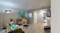 This single-floor residence offers a thoughtfully designed layout with a cohesive, modern aesthetic carried throughout. The living room serves as the heart of the space, featuring light wood-look flooring, crown molding, a textured ceiling, and a tiled fireplace flanked by a large mirror — all bathed in natural light from vertical blind-covered sliding doors. The kitchen is a well-organized galley-style space with gray cabinetry, white quartz countertops, a subway tile backsplash, and stainless steel appliances, including a refrigerator, range, and microwave. Adjacent to the kitchen, a dedicated dining nook provides a bright, intimate setting with a large window and ample room for a round table and seating. The bedroom is a calm retreat with a ceiling fan, generous natural light, and access to a spacious walk-in closet fitted with built-in wire shelving. The full bathroom is finished with large-format gray tile in the tub/shower surround, complemented by light flooring and a vanity. A hallway connects the rooms and offers additional storage. Light wood-look flooring, neutral gray walls, and crown molding are consistent throughout, giving the entire space a clean, unified character.