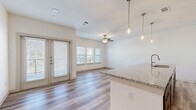 Located at 171 Town Park Dr in Conroe, TX, this well-appointed 2-bedroom, 2-bathroom residence offers a thoughtfully designed single-level layout with modern finishes throughout. The open-concept living, dining, and kitchen area serves as the heart of the home, featuring light wood-look flooring, a ceiling fan, and French doors that lead to a private balcony, filling the space with natural light. The kitchen is a standout, equipped with stainless steel appliances including a refrigerator, microwave, and range, complemented by white upper cabinetry, dark lower cabinetry, a subway tile backsplash, and a large granite-topped island with pendant lighting and an undermount sink. A dedicated pantry adds convenient storage. Both bathrooms are finished with granite countertops, dark cabinetry, and wood-look tile flooring. The primary bathroom features dual vanities and a soaking tub with large-format tile surround. The bedrooms are carpeted for comfort — the primary bedroom offers a generous footprint, while the second bedroom benefits from a triple window with outdoor views and a ceiling fan. Additional features include four closets, an in-unit laundry room, and a well-connected layout that maximizes functionality throughout.