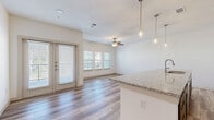 Located at 171 Town Park Dr in Conroe, TX, this well-appointed 2-bedroom, 2-bathroom residence offers a thoughtfully designed single-level layout with modern finishes throughout. The open-concept living, dining, and kitchen area serves as the heart of the home, featuring light wood-look flooring, a ceiling fan, and French doors that lead to a private balcony, filling the space with natural light. The kitchen is a standout, equipped with stainless steel appliances including a refrigerator, microwave, and range, complemented by white upper cabinetry, dark lower cabinetry, a subway tile backsplash, and a large granite-topped island with pendant lighting and an undermount sink. A dedicated pantry adds convenient storage. Both bathrooms are finished with granite countertops, dark cabinetry, and wood-look tile flooring. The primary bathroom features dual vanities and a soaking tub with large-format tile surround. The bedrooms are carpeted for comfort — the primary bedroom offers a generous footprint, while the second bedroom benefits from a triple window with outdoor views and a ceiling fan. Additional features include four closets, an in-unit laundry room, and a well-connected layout that maximizes functionality throughout.
