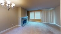 Located at 5716 N 33rd St in Tacoma, Washington, Unit 2C is a thoughtfully designed single-floor residence that combines functional living spaces with comfortable finishes throughout. The open layout connects the main living and dining areas seamlessly, with plush carpeting underfoot and warm neutral tones on the walls. The living room is anchored by a striking fireplace featuring a granite surround and white mantle, complemented by large windows and a sliding glass door that fill the space with natural light. The kitchen is well-equipped with rich wood cabinetry, a tile backsplash, light stone countertops, a double-basin stainless steel sink, and a stainless steel dishwasher, all set atop durable hardwood-style flooring. A pass-through peninsula provides additional counter space and connects the kitchen to the living area. A hallway leads to the bedrooms, each featuring soft carpeting, neutral walls, and windows with blinds that invite natural light. The primary bathroom includes a walk-in shower with a glass door, while the second bathroom offers a full tub-shower combination, vanity with stone countertop, and tile flooring. The unit provides a clean, move-in-ready environment with practical finishes suited for comfortable everyday living.