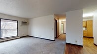 This single-floor residential unit offers a practical and well-organized layout designed for comfortable everyday living. The spacious living area is carpeted and features a wall-mounted air conditioning unit, a textured ceiling, and a large sliding glass door that opens onto a private balcony, allowing natural light to fill the room and providing views of the surrounding neighborhood. Adjacent to the living area, the entry foyer features warm hardwood flooring and a ceiling light fixture, creating a welcoming first impression with a solid wood front door.

The kitchen is efficiently designed with warm oak cabinetry, light countertops, hardwood flooring, and white appliances including an electric range and an over-the-range microwave, along with a stainless steel sink set into an L-shaped counter layout.

The bedrooms are carpeted and receive natural light through large windows that overlook the exterior. Each room includes wall-mounted heating units and baseboard heating, ensuring year-round comfort. At least one bedroom features a dedicated closet. The bathroom is neatly appointed with mosaic tile flooring, a full tub-shower combination with tiled surround, a toilet, and an oak vanity with a white countertop. Dark wood trim throughout the unit provides a consistent and cohesive design element.