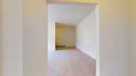 Located at 406 Prospect Ave in Hackensack, NJ, this single-floor residence offers a straightforward and functional layout with a clean, neutral aesthetic throughout. The living area is generously proportioned, featuring soft wall-to-wall carpeting and crisp white walls that create a bright, open feel. Large windows allow natural light to filter in, with views of surrounding greenery adding a pleasant outdoor connection. Baseboard heating runs throughout the carpeted rooms, ensuring comfortable warmth. The galley-style kitchen is efficiently designed with warm wood cabinetry on both sides, light countertops, a stainless steel sink, and white appliances including a refrigerator, stove, and over-the-range microwave. A window above the sink brings in natural light and garden views. The bedrooms are carpeted and well-sized, each equipped with windows and baseboard heating, with one room also featuring a wall-mounted air conditioning unit. The bathroom presents a clean, all-white design with tile flooring, a bathtub-shower combination, a vanity with sink, and a window that introduces natural light. Overall, the space presents a tidy, move-in-ready environment in a well-connected Hackensack location.
