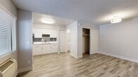 Located at 734 E Roger Rd in Tucson, AZ, this single-floor unit offers a thoughtfully organized layout that maximizes every inch of its compact footprint. Wood-look plank flooring runs seamlessly throughout the entire space, lending a clean, contemporary feel, while a textured ceiling adds a subtle visual element overhead.

The open living area is bright and straightforward, featuring a wall-mounted HVAC unit and a window that allows natural light to filter in, creating an airy atmosphere. A dedicated closet with a sliding door and hanging rod provides convenient built-in storage directly off the living space.

The kitchen is efficiently arranged with white cabinetry, white countertops, and a grey subway tile backsplash that adds a modern touch. It is equipped with a stainless steel refrigerator, an electric range with an overhead exhaust hood, and a double-basin sink — all accented by a window that brightens the workspace.

The bathroom is clean and functional, finished with the same wood-look flooring and featuring a single-sink vanity with white cabinetry, a mirror, and a full shower-tub combination with brushed nickel grab bars and fixtures. The overall design of this unit prioritizes practicality and a cohesive, updated aesthetic throughout.