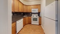 Located at 454 Heather Dr N in Mantua, New Jersey, this single-floor home offers a practical and comfortable layout designed for everyday living. The kitchen is thoughtfully equipped with warm honey-toned cabinetry, dark stone-look countertops, a full suite of white appliances including a dishwasher, electric range, over-the-range microwave, and refrigerator, all complemented by light hardwood flooring that adds a welcoming touch. Multiple carpeted rooms throughout the home provide a soft, comfortable underfoot feel, with neutral wall tones creating a clean, versatile backdrop. Several rooms benefit from natural light through windows fitted with blinds, offering both brightness and privacy. One room features an elegant chandelier, adding a refined decorative element. The bathroom includes a wood-vanity with mirror and Hollywood-style lighting, paired with classic small-tile flooring. A standout convenience is the in-unit stacked washer and dryer, neatly tucked within a dedicated space adjacent to the bathroom. The floor plan, as seen from the dollhouse view, reveals a well-organized layout with a central kitchen, connected living areas, and multiple separate rooms, making this home functional and easy to navigate.