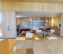 This impressive 3,900 square foot clubhouse in Missoula, Montana, is a testament to modern design and functionality. The single-story structure boasts seven distinct areas, each tailored to enhance community living. The fitness center is a highlight, equipped with top-of-the-line exercise machines and ample space for various workout routines. Floor-to-ceiling windows flood the area with natural light, creating an invigorating atmosphere for fitness enthusiasts.

The clubhouse's interior showcases a harmonious blend of natural and contemporary elements. Light wood paneling adorns the ceilings and walls, lending warmth to the space. The lounge areas feature plush, inviting furniture, including a tufted leather sectional that exudes comfort and style. Built-in shelving units and curated artwork add personality to the common spaces.

A striking feature is the expansive use of glass throughout the building, offering panoramic views of the surrounding landscape. This design choice not only brings the outdoors in but also creates a sense of openness and continuity. The multipurpose rooms are versatile, accommodating various community activities and gatherings.

The attention to detail is evident in every aspect, from the sleek bathroom facilities to the thoughtfully designed corridors. The clubhouse's layout promotes a seamless flow between different areas, encouraging social interaction while maintaining privacy where needed. This meticulously crafted space serves as a central hub for residents, combining luxury, functionality, and community spirit in one impressive package.