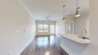 This single-floor residence offers a thoughtfully designed open-concept layout that seamlessly connects the living, dining, and kitchen areas. Rich hardwood flooring runs throughout, complemented by neutral-toned walls and crown molding that lend an elegant, cohesive feel to the space. Ceiling fans are present in the main living areas and bedrooms, enhancing both comfort and style.

The kitchen is a standout feature, equipped with crisp white shaker cabinetry, granite countertops, a marble-style subway tile backsplash, stainless steel appliances including a side-by-side refrigerator, and recessed lighting. A granite-topped island with pendant lighting bridges the kitchen and living area.

The living room is bright and airy, benefiting from large windows and a glass door that open to a private balcony with exterior views. The bedrooms are generously proportioned, each offering ample natural light from multiple windows. Both walk-in closets are outfitted with extensive wire shelving systems, providing abundant storage.

The primary bathroom features a dual-sink vanity with granite countertops, white cabinetry, and a large framed mirror with brushed nickel lighting. A secondary bathroom includes a soaking tub with white subway tile surround. Hardwood-style flooring extends through the bathrooms, maintaining design continuity throughout the residence.