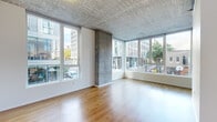Located in the heart of Portland's urban core, Unit 204 at 1720 SW 4th Ave is a thoughtfully designed residence that blends industrial character with modern finishes. The open living area is a standout, featuring expansive floor-to-ceiling windows on two sides that flood the space with natural light and frame dynamic views of the surrounding cityscape and tree-lined streets. Exposed concrete ceilings and structural concrete columns lend an authentic industrial aesthetic throughout, complemented by warm hardwood flooring.

The kitchen is efficiently designed with rich bamboo cabinetry, light-colored countertops, a stainless steel undermount sink, a built-in oven, an induction cooktop, and integrated appliances — all finished with clean, contemporary lines. The living and kitchen areas flow seamlessly together, creating an open and cohesive layout.

The bedrooms are carpeted for comfort, with exposed concrete ceilings continuing the industrial theme. One bedroom features a tall window with urban views and a built-in closet, while another room offers direct hallway access and flexible use. The bathrooms feature tile flooring, warm wood vanities, and clean white fixtures, including a full soaking tub in one. A hallway with hardwood flooring connects all areas of this well-appointed single-floor residence.