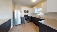 This single-floor residence offers a thoughtfully designed layout that balances open communal spaces with well-defined private areas. The heart of the home is an open-concept living and kitchen area, where warm hardwood-style flooring flows throughout. The kitchen is equipped with stainless steel appliances, including a refrigerator, electric range, and microwave, complemented by two-tone cabinetry featuring dark lower cabinets and crisp white upper cabinets. A kitchen island with pendant lighting provides additional counter space and serves as a natural divider between the kitchen and living area. Large windows allow natural light to fill the space.

The bedrooms feature neutral-toned carpet and windows that bring in natural light, with the primary bedroom including a ceiling fan. Double closets with paneled white doors offer generous storage. Additional bedrooms are carpeted and well-proportioned.

Both bathrooms are finished with tile flooring, dark vanity cabinetry, neutral countertops, and a tub/shower combination with chrome fixtures. A dedicated laundry closet houses a stacked washer and dryer unit, adding everyday convenience. Throughout, the space maintains a clean, modern aesthetic with neutral tones and consistent finishes.