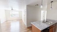 Located at Hershman Village in Morgantown, West Virginia, this single-floor, 3-bedroom, 1-bathroom unit offers a practical and functional layout. The kitchen is a standout feature, equipped with warm wood cabinetry, granite-style countertops, a double stainless steel sink, black appliances including a range and microwave, and a stainless steel refrigerator. Pendant lighting and hardwood-style flooring give the kitchen and adjacent living area a clean, welcoming feel. The three bedrooms are carpeted and finished with neutral, light-toned walls, each equipped with a ceiling fan for year-round comfort. The primary bedroom offers a notable amount of space, while the additional bedrooms are well-proportioned and functional. Select bedrooms feature windows that allow natural light and outdoor views of surrounding greenery, and at least one bedroom includes a closet with sliding panel doors. The bathroom is appointed with a wood-toned vanity, granite-style countertop, a large mirror, tile flooring, and a shower/tub combination. Throughout the unit, clean white trim and baseboards provide a consistent, tidy finish. The overall ambiance is bright, neutral, and move-in ready.