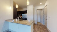 This well-appointed two-story residence combines modern finishes with a functional layout across both levels. The heart of the home is an open-concept kitchen and living area, where rich hardwood-style flooring flows throughout. The kitchen is outfitted with dark espresso cabinetry, granite countertops, a large center island with a built-in sink, stainless steel appliances including a refrigerator, microwave, and electric range, and a tasteful tile backsplash. Pendant lighting accents the island, adding warmth to the space. The living area is bright and airy, featuring a ceiling fan, access to an outdoor balcony or patio through a glass door, and multiple windows that allow natural light to fill the room. The primary bathroom is finished with granite countertops, dark cabinetry with modern hardware, elegant tile flooring, a soaking tub with white subway tile surround, and direct access to a spacious walk-in closet. Bedroom spaces are carpeted for comfort and offer generous natural light through large windows. The residence also includes an attached garage with an automatic opener, providing secure, convenient parking and additional storage space.