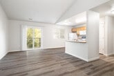 This well-appointed 2-bedroom, 2-bathroom residence in Caldwell, Idaho offers a thoughtfully designed single-floor layout with modern finishes throughout. The open-concept living and kitchen area is anchored by vaulted ceilings and warm wood-style flooring, creating a bright and airy atmosphere. Large sliding glass doors lead to a private balcony overlooking a lush, tree-lined green space, flooding the living area with natural light. The kitchen features warm-toned cabinetry, a peninsula with a sink, and full appliances including a refrigerator and range, with a window that brings in additional natural light. Both bedrooms offer comfortable proportions, with the primary bedroom boasting vaulted ceilings and generous closet space complete with wire shelving systems. The second bedroom includes a sliding double-door closet and a bright window. Each bathroom is equipped with a full tub-shower combination. A dedicated in-unit laundry room with a full-size washer and dryer adds everyday convenience. Two closets provide ample storage throughout the home. The consistent wood-style flooring, neutral color palette, and clean finishes give the entire space a cohesive, move-in-ready appeal.