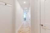 This modern single-story, 2-bedroom, 2-bathroom home in Austin, TX offers a thoughtfully designed layout filled with natural light and contemporary finishes. Light wood flooring flows seamlessly throughout the entire space, complementing the crisp white walls and clean aesthetic. The entrance leads down a bright hallway with recessed lighting, opening into the heart of the home. The combined kitchen and living area is a standout feature, showcasing shaker-style cabinetry, a classic subway tile backsplash, stainless steel appliances, and a large central island with white quartz countertops and globe pendant lighting overhead — ideal for both cooking and casual dining. The bedrooms are generously proportioned, bathed in natural light from windows with views of the surrounding neighborhood. Each room is served by a dedicated closet with built-in shelving and hanging rods for ample storage. The primary bathroom features a dual-sink vanity with brushed nickel hardware, a large mirror, and a soaking tub clad in subway tile. A dedicated laundry room houses a full-size washer and dryer. The home's cohesive design, abundant natural light, and practical layout make it an inviting and functional living space.