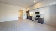 This 470 square foot apartment in Concord, California, offers a contemporary living space designed for efficiency and style. The open-concept floor plan maximizes the use of space, creating a seamless flow between the living area and kitchen. The kitchen is a standout feature, boasting a sleek design with a mix of white and dark wood cabinetry, stainless steel appliances, and a subway tile backsplash. Recessed lighting throughout ensures ample illumination.

The living area is spacious and versatile, with light-colored walls and large windows that flood the space with natural light. The bathroom continues the modern aesthetic with a floating vanity, large mirror, and a glass-enclosed shower. A neutral color palette and light gray wood-look flooring unify the space, creating a cohesive and inviting atmosphere.

Storage solutions include a closet and additional kitchen cabinetry. The apartment's layout efficiently incorporates all essential living spaces within its compact 470 square feet, making it an ideal choice for those seeking a low-maintenance, high-style urban dwelling.