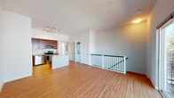 This two-floor space is designed with an open, functional layout that maximizes comfort and usability. The upper level showcases a generously sized open-concept living and kitchen area, anchored by warm hardwood-style flooring that runs throughout. A white-railed staircase provides a clean architectural detail while connecting the two levels seamlessly.

The kitchen is a standout feature, outfitted with rich dark cherry wood cabinetry, granite countertops, and a full suite of stainless steel appliances including a refrigerator, electric range, built-in microwave, and dishwasher. A peninsula with a granite surface extends the counter space and provides an ideal spot for casual dining or meal prep. Track lighting overhead ensures the kitchen remains well-lit at all times.

Adjacent to the kitchen, the open living area offers ample room to configure a variety of furniture arrangements. A dedicated laundry closet and utility panel are conveniently tucked nearby, adding practical functionality to the space.

The bathroom features light tile flooring, a granite-topped vanity with dark wood cabinetry, and a large window that floods the room with natural light, creating a bright and airy atmosphere. The clean white walls throughout the space contribute to a fresh, modern ambiance overall.