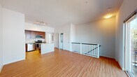 This two-floor space is designed with an open, functional layout that maximizes comfort and usability. The upper level showcases a generously sized open-concept living and kitchen area, anchored by warm hardwood-style flooring that runs throughout. A white-railed staircase provides a clean architectural detail while connecting the two levels seamlessly.

The kitchen is a standout feature, outfitted with rich dark cherry wood cabinetry, granite countertops, and a full suite of stainless steel appliances including a refrigerator, electric range, built-in microwave, and dishwasher. A peninsula with a granite surface extends the counter space and provides an ideal spot for casual dining or meal prep. Track lighting overhead ensures the kitchen remains well-lit at all times.

Adjacent to the kitchen, the open living area offers ample room to configure a variety of furniture arrangements. A dedicated laundry closet and utility panel are conveniently tucked nearby, adding practical functionality to the space.

The bathroom features light tile flooring, a granite-topped vanity with dark wood cabinetry, and a large window that floods the room with natural light, creating a bright and airy atmosphere. The clean white walls throughout the space contribute to a fresh, modern ambiance overall.