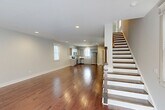 Located at 892 Portside Pl in Chattanooga, TN, this three-bedroom, four-bathroom home is thoughtfully arranged across three floors. The ground level houses an attached garage alongside utility space, providing practical storage and parking. The main living floor is an open-concept layout combining the living room, dining area, and kitchen into one expansive, light-filled space. Rich hardwood floors flow throughout, complementing the neutral gray walls and recessed lighting overhead. The kitchen features gray shaker-style cabinetry, white countertops, and a full suite of stainless steel appliances, including a range, microwave, dishwasher, and refrigerator. A staircase with a classic wood banister and white balusters connects all three levels, with natural light filtering in from nearby windows. A half bathroom is conveniently located on this floor. The upper floor is home to three carpeted bedrooms, including a generously sized primary suite, along with additional bathrooms featuring tub-shower combinations. Each bedroom offers a calm, neutral palette with ample closet space. A dedicated laundry area adds everyday convenience. The home's clean architectural lines, consistent finishes, and well-organized layout make it a highly functional and comfortable residence in the heart of Chattanooga.