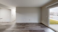 Located at 1800 Commerce Pkwy in La Grange, Kentucky, this two-bedroom, two-bathroom single-floor residence offers a well-organized and functional layout. The open-concept living, dining, and kitchen area serves as the heart of the home, featuring rich dark-toned luxury vinyl plank flooring and a sliding glass door that fills the space with natural light and provides outdoor views. The kitchen is outfitted with a mix of light and dark cabinetry, light-toned countertops, stainless steel appliances including a refrigerator, dishwasher, and range, and a peninsula island ideal for additional prep space or casual dining. A central hallway connects the main living area to the two carpeted bedrooms, both of which offer a quiet and comfortable feel. The generously sized primary bedroom provides ample space and includes access to closet storage. Both bathrooms feature wood-toned vanities, light countertops, and durable LVP flooring, maintaining a consistent and cohesive aesthetic. A dedicated laundry room with washer/dryer hookups adds everyday convenience. With neutral wall tones, clean white trim, and four closets spread throughout, this home offers practical storage and a move-in-ready appeal.