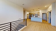 This three-floor space showcases a contemporary design aesthetic defined by clean lines, light wood-style flooring, and a bright, neutral color palette throughout. The kitchen serves as a central highlight, featuring a large island with a white quartz countertop, an integrated sink with a commercial-style faucet, and stainless steel appliances including a French door refrigerator, electric range, and microwave. Taupe shaker-style cabinetry pairs with a classic white subway tile backsplash, while geometric pendant lights add a modern decorative touch. A barn door accent and in-unit laundry add functional convenience nearby.

The open-concept layout flows seamlessly between the kitchen and living areas, where a sleek black horizontal-rail staircase connects the floors. Upper levels benefit from elevated windows that draw in generous natural light, illuminating the airy, open spaces. Bedrooms are well-proportioned, featuring large black-framed windows with outdoor views and ceiling fans for comfort.

Bathrooms are finished with clean, modern details, including dual-sink vanities with white quartz countertops, warm wood cabinetry, matte black hardware, and a combination tub and shower. The overall ambiance is fresh, modern, and move-in ready.