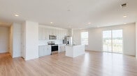 Located at 3025 Woodward Crossing Blvd in Buford, GA, this well-appointed 2-bedroom, 2-bathroom residence offers a bright, modern design with a clean, neutral palette throughout. The open-concept kitchen and living area serves as the heart of the home, featuring crisp white shaker cabinetry, granite countertops, stainless steel appliances including a refrigerator with ice maker, electric range, and microwave, along with a central island with a sink — ideal for both everyday living and entertaining. Light wood-look flooring flows throughout the main living areas, complementing the abundant natural light that pours in through large windows and a sliding glass door that opens to a balcony with outdoor views. The spacious primary bedroom includes plush carpet, a sliding glass door, and access to a well-designed en-suite bathroom featuring a dual-sink granite vanity, light-toned cabinetry, and a large mirror with stylish lighting fixtures. The second bedroom offers carpet flooring, a ceiling fan, and a bright window. Both bedrooms are served by generous walk-in closets with wire shelving systems. A clean hallway connects the private quarters, and the overall layout is efficiently designed to maximize comfort and functionality.