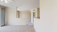 This efficiently designed 660-square-foot, one-bedroom, one-bathroom apartment is laid out entirely on a single floor. The combined kitchen and living area serves as the heart of the unit, featuring light tile flooring, a granite-topped breakfast bar peninsula, light wood cabinetry, a built-in wine rack, and white appliances including a refrigerator and electric range. A built-in microwave adds convenience to the well-equipped kitchen. Crown molding and a ceiling fan with light fixture accent the living area, which opens to a private balcony through large sliding glass doors, offering abundant natural light and outdoor views of surrounding greenery. The 180-square-foot primary bedroom is carpeted and includes a ceiling fan, a window for natural light, and direct access to two closets as well as the full bathroom. The bathroom is finished with tile flooring, a granite-topped vanity with an undermount sink, light wood cabinetry, and a tiled shower/tub combination. Two closets provide ample storage throughout the unit. The apartment's neutral warm-beige color palette, consistent finishes, and functional layout create a clean, cohesive living environment suitable for individuals or couples.