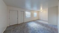 Located at 3541 Evans Ave in Fort Myers, Florida, this two-bedroom, one-bathroom unit offers a straightforward and functional single-floor layout. The living area features neutral-toned carpet, a ceiling fan, and an open connection to the kitchen, creating a cohesive and easy-to-navigate space. Natural light filters in through windows dressed with vertical blinds, brightening the interior throughout the day.

The kitchen is equipped with warm wood-toned cabinetry offering ample upper and lower storage, a double-basin sink, and white appliances including an electric range, over-the-range microwave, and full-size refrigerator. The tile flooring in the kitchen provides a practical contrast to the carpeted areas elsewhere in the unit.

The spacious primary bedroom benefits from natural light through dual windows and includes a built-in closet. The second bedroom is more intimate in scale and features a dedicated closet with louvered bifold doors, complete with shelving. A hallway connects the bedrooms to the shared bathroom, which is appointed with a vanity, single-basin sink, and a large mirror with overhead lighting. Textured walls throughout the unit add subtle character to the otherwise clean, neutral palette.