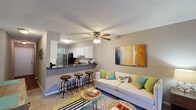 Located at 101 Echo Glen Dr in Winston-Salem, NC, this single-floor residence offers a well-organized layout designed for comfortable everyday living. The open-concept living area serves as the heart of the home, featuring plush carpeting, a ceiling fan, a textured ceiling, and a corner fireplace with a sleek black surround — an inviting focal point for the room. Colorful wall art adds a lively touch to the neutral, warm-toned walls.

The kitchen is positioned adjacent to the living space and features white cabinetry, dark countertops, stainless steel appliances, and an extended breakfast bar with barstool seating — ideal for casual dining or entertaining. The seamless connection between the kitchen and living area enhances the open feel of the space.

The unit includes multiple bedrooms, each with carpeted floors, natural light from window treatments, and ample room for furnishings. One bedroom features a bold accent wall in a vibrant green, while another showcases a calming blue-grey palette, both adding distinct character to their respective spaces.

Two bathrooms are finished with wood-look flooring, white vanities with granite-style countertops, and tub-shower combinations, offering clean and functional design throughout. The overall layout is practical and cohesive, making this Winston-Salem residence a comfortable and well-appointed living space.