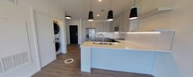 This contemporary 610 square foot apartment offers a harmonious blend of style and functionality. The heart of the home is an open-concept living area, seamlessly integrating the kitchen and living room. The kitchen boasts sleek white cabinetry, stainless steel appliances, and a generous island with a sink, perfect for meal preparation and casual dining. Overhead, three striking black pendant lights add a touch of modern elegance.

The bedroom, measuring 120 square feet, features large windows that flood the space with natural light and provide picturesque views. A sliding glass door leads to a private balcony, offering an outdoor retreat and expanding the living space. The bathroom showcases a modern design with a glass-enclosed shower and crisp white tiling.

Throughout the apartment, warm wood-look flooring creates a cohesive and inviting atmosphere. The neutral color palette, predominantly whites and light grays, contributes to a bright and airy feel. Strategic recessed lighting and large windows ensure the space is well-lit and welcoming.

This single-floor residence also includes a closet for storage, and its efficient layout maximizes the use of space, making it an ideal home for those seeking a contemporary urban lifestyle.