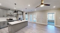 Located at 437 Roanoke Rd in Daleville, Virginia, this well-appointed 2-bedroom, 2-bathroom single-floor home offers a thoughtfully designed open-concept layout. The combined living, dining, and kitchen area serves as the heart of the home, featuring light luxury vinyl plank flooring, crown molding, recessed lighting, and ceiling fans throughout. The kitchen is a standout, showcasing gray shaker-style cabinetry, white quartz countertops, a subway tile backsplash, a center island with pendant lighting, and stainless steel appliances. French doors lead to a private balcony, filling the space with natural light. The generously sized primary bedroom offers plush carpeting, a ceiling fan, and access to a closet. The second bedroom also features carpet flooring, large windows with outdoor views, and its own ceiling fan. Both bathrooms are finished with gray vanities and white quartz countertops, with one including a shower-tub combo. A dedicated laundry area houses a full-size washer and dryer. Three closets provide ample storage throughout. The overall aesthetic is clean, modern, and move-in ready, with a neutral color palette that lends itself to a bright and welcoming atmosphere.