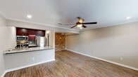 This single-story, one-bedroom, one-bathroom unit blends modern finishes with charming character details throughout its well-designed layout. The open living area is a standout space, featuring warm wood-look flooring, crown molding, and a ceiling fan overhead. A striking exposed brick accent wall adds a distinctive industrial touch, creating visual interest against the neutral-toned walls. The living area flows seamlessly into the kitchen via a granite-topped breakfast bar, making the space feel open and connected.

The kitchen is well-equipped with rich, dark cabinetry, granite countertops, a glass tile backsplash, and a full suite of stainless steel appliances, including a gas range, over-the-range microwave, and refrigerator. The bedroom offers a comfortable retreat with plush carpet, crown molding, a ceiling fan, a window for natural light, and access to a walk-in closet with built-in shelving. The bathroom features a granite-topped vanity with dark cabinetry, a tub-shower combination, wood-look flooring, and a skylight that brings in natural light. Overall, the unit presents a cohesive blend of classic architectural details and contemporary upgrades.