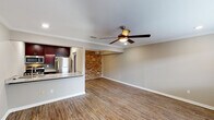 This single-story, one-bedroom, one-bathroom unit blends modern finishes with charming character details throughout its well-designed layout. The open living area is a standout space, featuring warm wood-look flooring, crown molding, and a ceiling fan overhead. A striking exposed brick accent wall adds a distinctive industrial touch, creating visual interest against the neutral-toned walls. The living area flows seamlessly into the kitchen via a granite-topped breakfast bar, making the space feel open and connected.

The kitchen is well-equipped with rich, dark cabinetry, granite countertops, a glass tile backsplash, and a full suite of stainless steel appliances, including a gas range, over-the-range microwave, and refrigerator. The bedroom offers a comfortable retreat with plush carpet, crown molding, a ceiling fan, a window for natural light, and access to a walk-in closet with built-in shelving. The bathroom features a granite-topped vanity with dark cabinetry, a tub-shower combination, wood-look flooring, and a skylight that brings in natural light. Overall, the unit presents a cohesive blend of classic architectural details and contemporary upgrades.