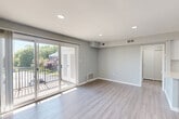 Located at 1000 Cedartree Lane in Claymont, Delaware, this single-floor, 2-bedroom, 1-bathroom residence offers a clean, modern aesthetic throughout. The open-concept living room is bright and welcoming, featuring light-toned hardwood-style flooring, recessed lighting, and a full wall of sliding glass doors that open onto a private balcony with outdoor views. The adjacent kitchen is thoughtfully designed with dark espresso cabinetry, a white subway tile backsplash, granite countertops, a granite-topped breakfast bar, black appliances including a gas range and dishwasher, and tile flooring. Both bedrooms are carpeted and bathed in natural light from windows, with the spacious primary bedroom offering generous room for furnishings. A ceiling fan in the secondary bedroom adds comfort. The bathroom features a full soaking tub with a handheld showerhead, accented by large-format neutral tile surround. A dedicated in-unit laundry area houses a full-size washer and dryer. Two closets provide ample storage, and the hallway connects all rooms efficiently. The space is finished with neutral gray walls and crisp white trim throughout, creating a cohesive, contemporary feel.