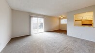 Located at 4424 NW Hon Dr in Riverside, MO, this 1-bedroom, 1-bathroom unit offers a practical and comfortable single-floor layout. The living room is the heart of the space, featuring plush carpeting, a ceiling fan, and abundant natural light from a large sliding glass door that opens to an outdoor area. A pass-through window connects the living area to the kitchen, which is equipped with white cabinetry and appliances, creating an open and airy feel without sacrificing defined spaces. The adjacent dining or transition area features wood-style flooring, adding a warm contrast to the carpeted rooms. The hallway leads to the generously proportioned bedroom, which features soft carpet, a wide window with outdoor views, and ample closet space including a full-width sliding-door closet and an additional open closet with a rod for hanging storage. The bathroom is clean and functional, appointed with white tile surrounding a full soaking tub and shower combination, complemented by a toilet and neutral finishes throughout. Textured ceilings are consistent throughout the unit, and neutral wall tones provide a versatile backdrop. The overall layout is efficient and well-connected, making the most of the available space for comfortable everyday living.