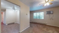 Located at 1743 Market Ave N in Canton, Ohio, this single-floor unit offers a straightforward, functional layout across several distinct living areas. The living space is finished with wall-to-wall carpet and neutral beige walls, creating a subdued, practical ambiance. Ceiling fans with integrated lighting fixtures are present throughout, contributing to both air circulation and general illumination. Textured ceilings add a classic finishing detail consistent across the rooms.

The main living area features a window with horizontal blinds, allowing natural light to filter in, along with a wall-mounted air conditioning unit and baseboard heating for year-round climate control. A second carpeted room, accessible through an open doorway, offers additional flexible living space with its own ceiling fan and multiple windows overlooking outdoor greenery.

The kitchen is equipped with white cabinetry featuring dark hardware, a dark laminate countertop, a double stainless steel sink, and a freestanding electric range with an overhead exhaust vent. The flooring transitions to a durable tile-style surface in this area.

The bathroom includes a single-sink vanity with a marble-patterned countertop, a framed mirror, a full tub-shower combination, and tile-style flooring. An entry room with carpet and a ceiling fan provides a functional transition upon entering the unit.