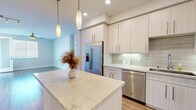 Located at 13385 Highlands Pl in San Diego's desirable Carmel Valley neighborhood (92130), this single-story residence showcases a clean, modern aesthetic with thoughtfully designed living spaces and quality finishes throughout.

The kitchen is a standout feature, equipped with light-toned flat-front cabinetry, stone-look countertops, and a full suite of stainless steel GE appliances including a gas range, microwave, dishwasher, and French door refrigerator. A tile backsplash with a subtle linear pattern adds texture, while pendant lighting over the center island enhances both function and style. Wood-look flooring flows through the main living areas, complementing the bright, neutral color palette.

The spacious living area benefits from natural light through large windows with blinds and features a ceiling fan and access to an outdoor space. Bedrooms are carpeted and include generous closet space, with one bedroom offering a walk-in closet with built-in shelving.

Two bathrooms serve the home: one with a sleek glass-enclosed walk-in shower and stone tile, and another with a tub-shower combination. Both feature light wood vanities with stone countertops. An in-unit stacked washer and dryer adds everyday convenience, completing this well-appointed Carmel Valley residence.