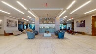 Located at 150 River St in Hackensack, New Jersey, this single-floor amenity space presents a refined, contemporary design highlighted by polished marble-look tile flooring, geometric linear lighting, and carefully curated furnishings throughout. The grand lobby serves as the centerpiece, featuring a striking reception desk clad in marble with an illuminated gold lattice front panel, set against a backdrop of vertical sculptural wall elements. Expansive large-format marble flooring extends through the space, lending an air of understated luxury.

Multiple seating areas are distributed thoughtfully across the floor, including clusters of plush blue swivel chairs arranged around low coffee tables, as well as relaxed lounge vignettes with neutral-toned accent chairs and curated décor. A decorative floor-to-ceiling shelving unit provides an artistic focal point in one corridor, accompanied by sculptural pendant lighting and original artwork.

The entertainment zone transitions into wood-look tile flooring and features a pool table, foosball table, suspended egg chairs, and direct views to a landscaped outdoor area through floor-to-ceiling windows. A glass-enclosed conference room with a long table offers a professional setting. The overall ambiance is polished, welcoming, and distinctly upscale.