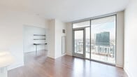 Located in Chicago's vibrant Lincoln Park/Old Town neighborhood, this one-bedroom, one-bathroom unit at 1457 North Halsted Street offers a well-designed layout across a single floor. Rich hardwood flooring runs throughout, complementing the clean, modern aesthetic of the space.

The open-concept living room and kitchen area is anchored by dramatic floor-to-ceiling windows and a glass-panel balcony door that floods the space with natural light and provides sweeping views of the Chicago skyline. Built-in shelving and a wall-mounted desk add functional, space-saving character to the living area.

The kitchen is appointed with rich dark wood cabinetry, stainless steel appliances including a gas range, microwave, and full-size refrigerator, and a large peninsula with a light stone countertop and an integrated sink — ideal for both cooking and casual dining.

The bedroom features its own floor-to-ceiling windows with continued balcony access, delivering an abundance of natural light and unobstructed city views. The bathroom includes a glass-enclosed walk-in shower and tile flooring. A dedicated closet area houses a stacked in-unit washer and dryer, adding everyday convenience to this smartly designed urban residence.
