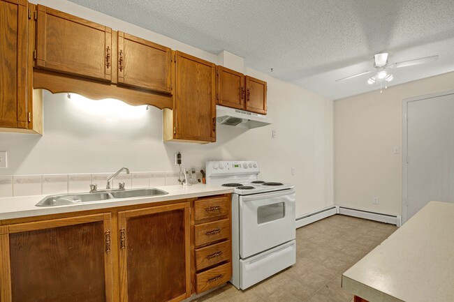 A kitchen with white appliances and wood cabinetry - Broadmoor