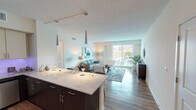 This single-floor residence offers a contemporary open-concept layout connecting the kitchen, dining, and living areas into one cohesive space. The kitchen is well-appointed with stainless steel appliances including a refrigerator, range, microwave, and dishwasher. Dark espresso lower cabinetry contrasts with light upper cabinets, complemented by quartz countertops and a generously sized island with pendant lighting overhead. Subtle under-cabinet lighting adds ambiance throughout. Hardwood-style flooring runs throughout the main living areas, enhancing the modern aesthetic.

The living room is bright and open, benefiting from large sliding glass doors that provide direct access to a private balcony and allow ample natural light to fill the space. Two bedrooms are included; the primary bedroom features plush carpeting, a ceiling fan, large windows with outdoor views, and a walk-in closet. The secondary bedroom is comfortably sized with a ceiling fan.

Both bathrooms are finished with quartz vanity countertops, light cabinetry, and wood-style flooring. The primary bathroom includes a glass-enclosed shower, while the secondary bathroom offers a full soaking tub with a shower combination. The overall ambiance is clean, bright, and contemporary throughout.