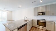 Located at 620 W Due West Ave in Nashville, TN, this thoughtfully designed single-floor unit offers a clean, modern aesthetic throughout. The open-concept layout seamlessly connects the kitchen and living area, maximizing the use of space while maintaining a bright, airy feel. Warm-toned luxury vinyl plank flooring runs throughout, complementing the crisp white walls and contemporary finishes.

The kitchen is a standout feature, equipped with granite countertops, gray shaker-style cabinetry extending to the ceiling, a white subway tile backsplash, and a full suite of stainless steel appliances including a refrigerator, range, microwave, and dishwasher. A peninsula with an undermount sink adds prep space and serves as a natural divider between the kitchen and the open living area. The living space is bright and welcoming, featuring a ceiling fan, recessed lighting, and a sliding glass door that fills the room with natural light.

The bathroom is well-appointed with granite countertops, gray cabinetry, a tub-shower combination, and recessed lighting. A dedicated laundry area with wire shelving provides added convenience and storage. The overall design is clean and contemporary, making this a functional and attractive Nashville residence.