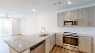 Located at 620 W Due West Ave in Nashville, TN, this thoughtfully designed single-floor unit offers a clean, modern aesthetic throughout. The open-concept layout seamlessly connects the kitchen and living area, maximizing the use of space while maintaining a bright, airy feel. Warm-toned luxury vinyl plank flooring runs throughout, complementing the crisp white walls and contemporary finishes.

The kitchen is a standout feature, equipped with granite countertops, gray shaker-style cabinetry extending to the ceiling, a white subway tile backsplash, and a full suite of stainless steel appliances including a refrigerator, range, microwave, and dishwasher. A peninsula with an undermount sink adds prep space and serves as a natural divider between the kitchen and the open living area. The living space is bright and welcoming, featuring a ceiling fan, recessed lighting, and a sliding glass door that fills the room with natural light.

The bathroom is well-appointed with granite countertops, gray cabinetry, a tub-shower combination, and recessed lighting. A dedicated laundry area with wire shelving provides added convenience and storage. The overall design is clean and contemporary, making this a functional and attractive Nashville residence.