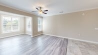 This single-floor residence at 920 Seasons Drive in Gastonia, NC offers a well-organized layout with a clean, contemporary aesthetic throughout. The kitchen serves as a central feature, equipped with rich dark cabinetry, granite countertops, stainless steel appliances including a refrigerator, range, and built-in microwave, and a peninsula with pendant lighting overhead. Light tile flooring in the kitchen transitions into wood-style plank flooring across the living and bedroom areas, maintaining a cohesive visual flow.

The living area receives ample natural light through large windows fitted with horizontal blinds, offering views of the surrounding neighborhood. A set of glass doors connects the living space to an outdoor area, further enhancing the sense of openness. The dining area features tile flooring, a decorative chandelier, and chair-rail molding along the walls.

Bedrooms are finished with wood-style flooring and neutral tones, with windows admitting generous daylight. At least one bedroom includes access to a walk-in closet with wire shelving. The bathroom features a dual-sink granite vanity with dark cabinetry, a large mirror, and a tiled shower. A dedicated laundry area with washer and dryer hookups and overhead shelving adds functional convenience.