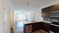 Located at Flint Street in Lenexa, Kansas, this single-floor unit showcases a contemporary design with a thoughtful open-concept layout. The kitchen serves as a central highlight, featuring dark espresso cabinetry that extends to the ceiling, quartz countertops with subtle veining, and a large island with an undermount sink and pendant lighting overhead. Stainless steel appliances, including a side-by-side refrigerator with ice maker, electric range, built-in microwave, and dishwasher, complete the well-appointed space. The kitchen flows seamlessly into the living area, which is finished with wood-look flooring and a ceiling fan, while large windows invite natural light throughout.

The bedrooms are carpeted for comfort and feature ceiling fans, generous windows, and sliding glass doors leading to private balconies with views of the surrounding community. The primary bathroom is appointed with a dual-sink quartz vanity, dark cabinetry, wood-look flooring, and a tiled walk-in shower with a glass sliding door. A secondary bathroom mirrors the same refined aesthetic, offering a quartz vanity and a tiled tub-shower combination, rounding out a cohesive and modern interior.